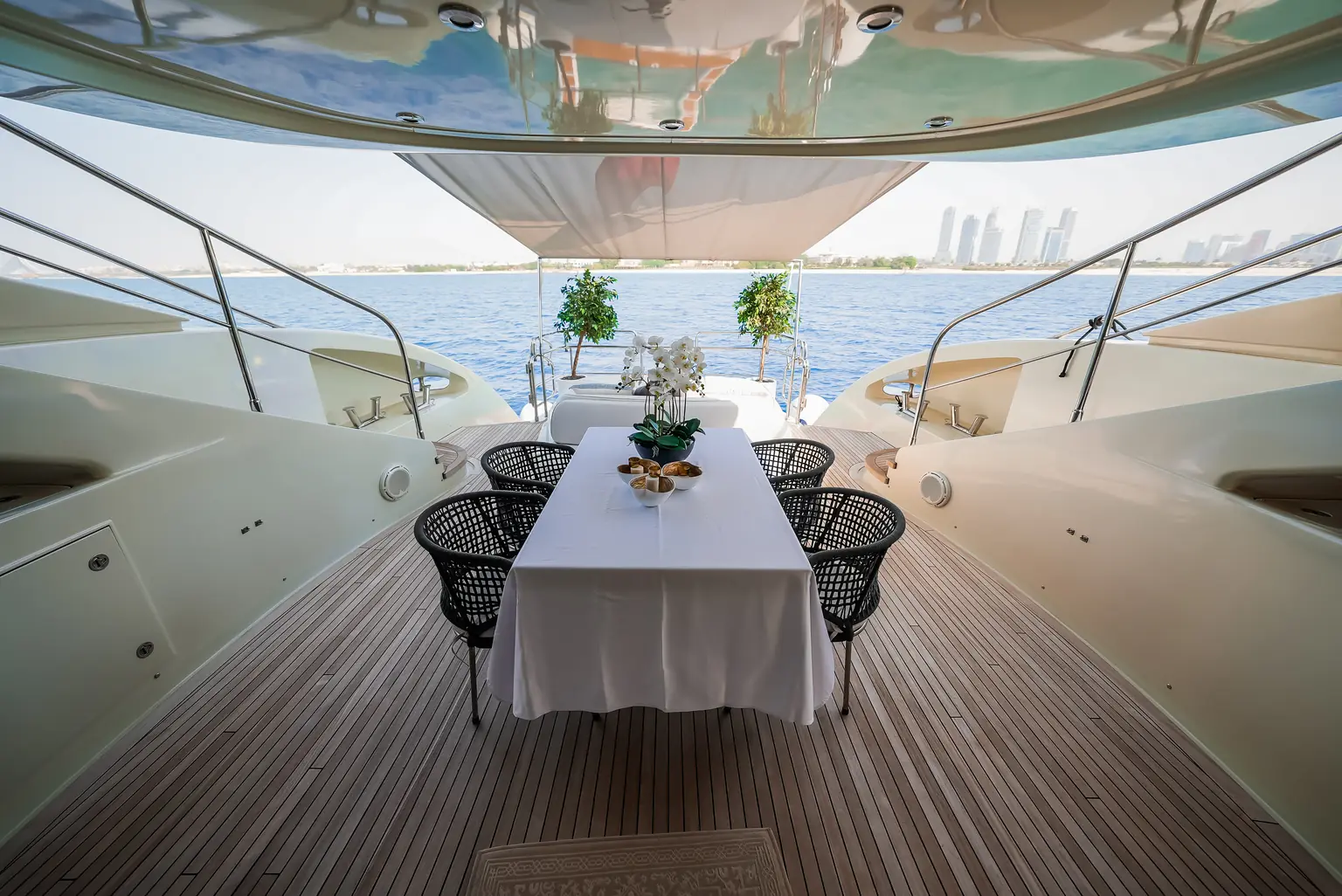 Aft deck dining table laid for guests under the shade of the deck above