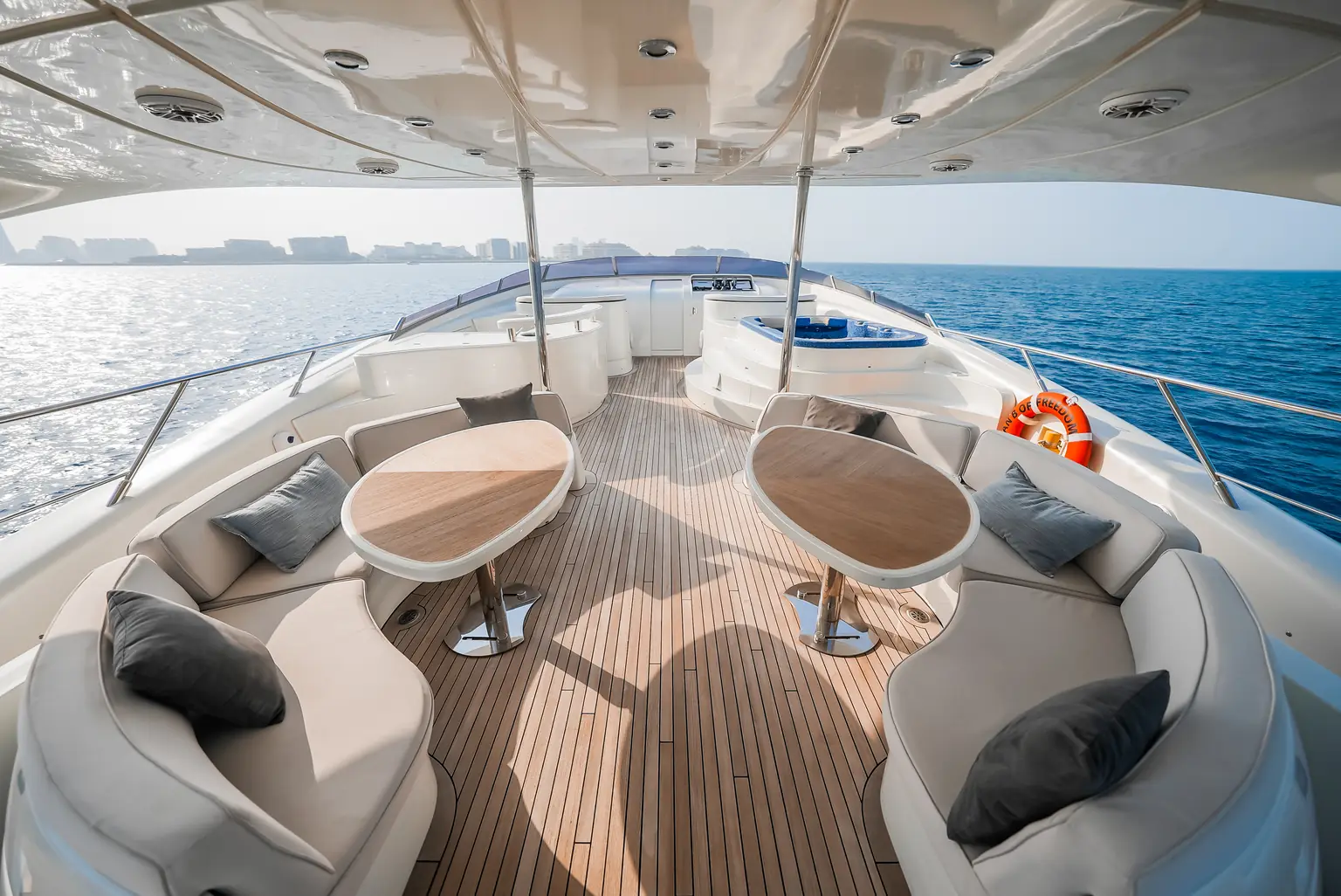 Upper deck seating with low round tables and cushioned chairs on teak