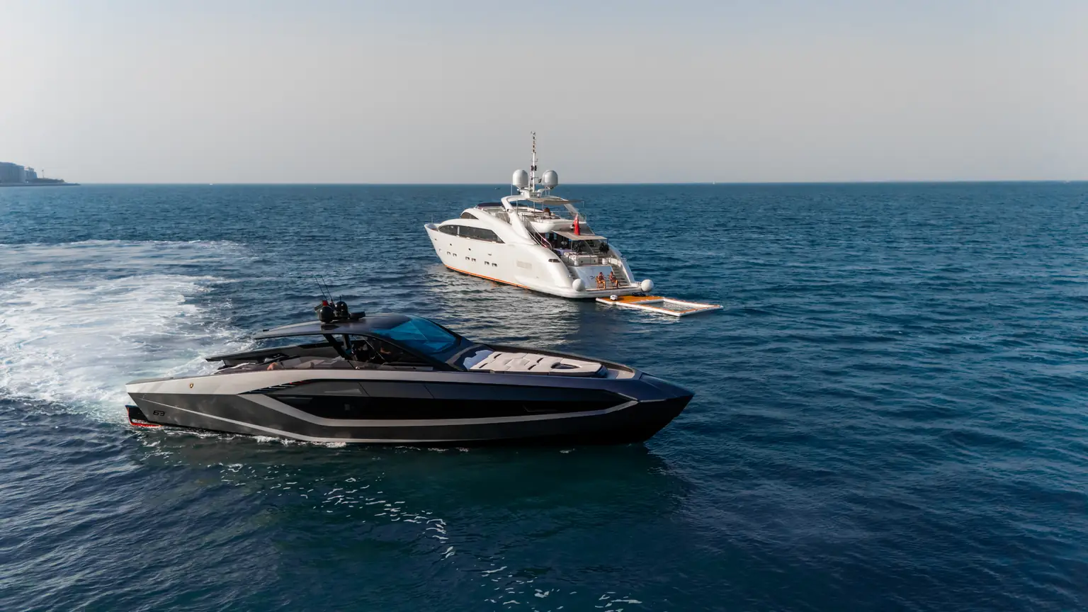 Plan B of Freedom at anchor off Dubai as another yacht passes in the foreground