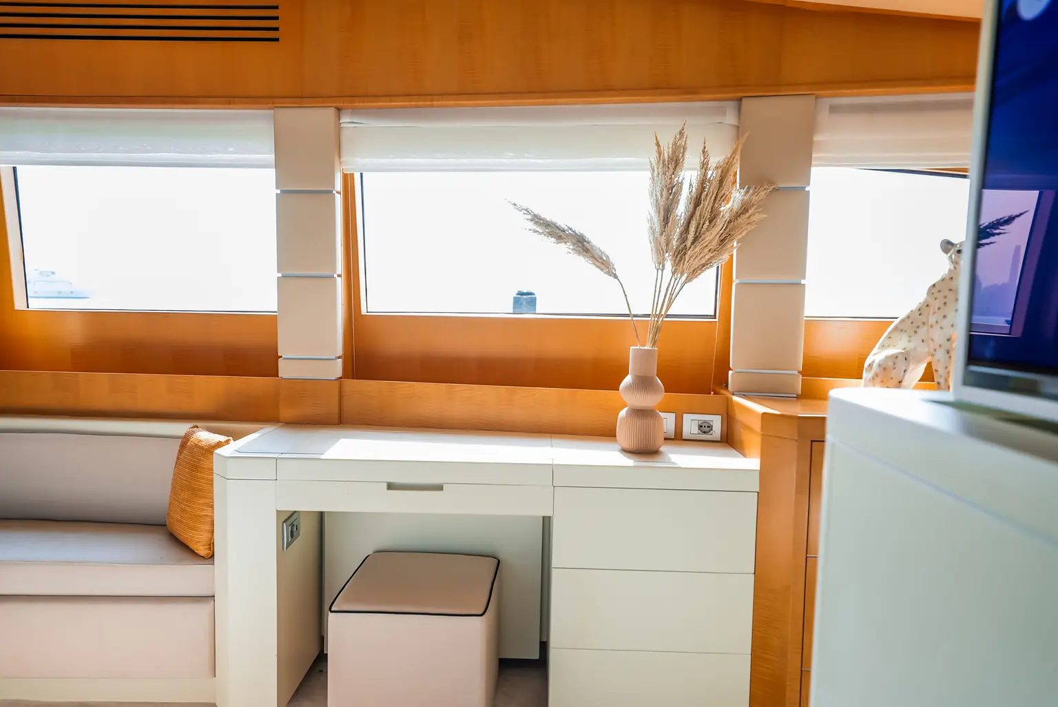 Cabin vanity with fitted drawers, a stool and a long window above