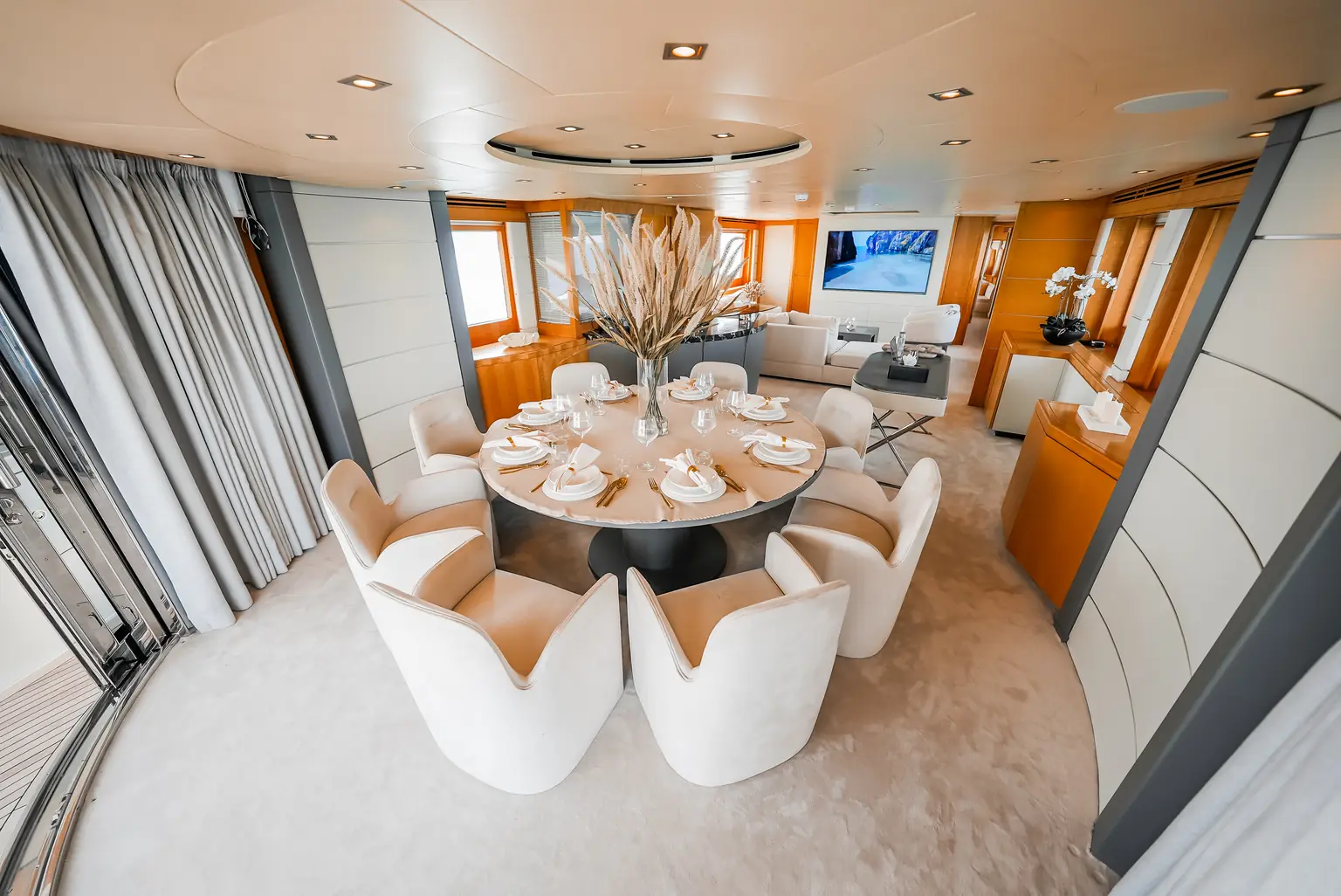 Interior dining area with a round table laid for guests beneath a recessed ceiling light